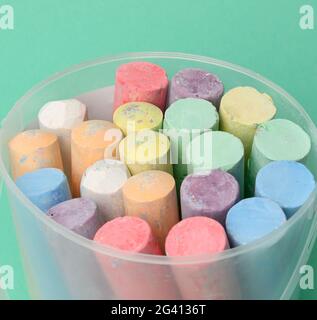 Multicolored chalk in a plastic bucket on a green background, Stock Photo