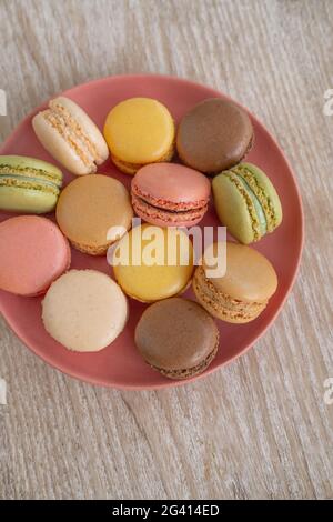 Macarons top view on pink plate against wooden background retro cute desserts. Selections of pastel color macaron Stock Photo