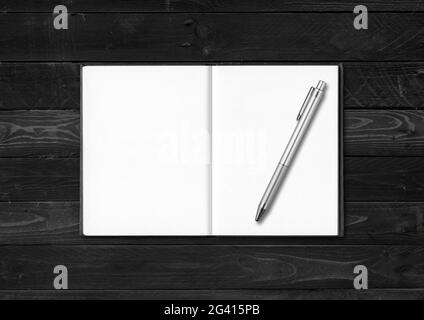 Blank open notebook and pen isolated on black wood background Stock Photo