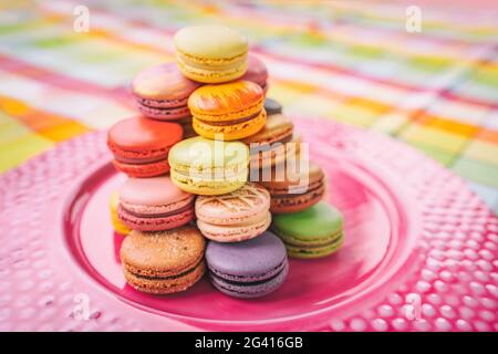 Macarons tower on dessert plate at home. Cute retro vintage pink plate on checkered tablecloth easter table decoration home kitchen. Assortment of Stock Photo