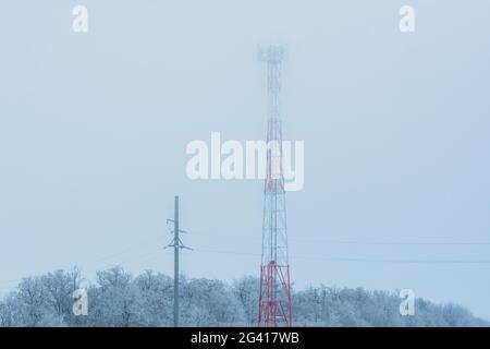 Cell tower in the winter fog close-up. Telecommunications towers with wireless antennas in rime. Antennas for information transmission, mobile communi Stock Photo