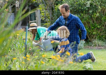 Caucasian father and son in garden watering plants and gardening with their family Stock Photo