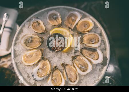 Oysters platter at restaurant fresh oyster on ice plate from Canada. Canadian seafood top view Stock Photo