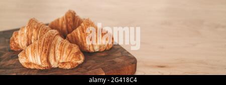 Fresh baked croissants on wooden board banner background. French pastries from bakery Stock Photo