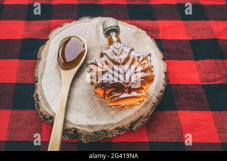 Maple syrup bottle Quebec cultural food traditional harvest top view on buffalo dining tablecloth background. Canada grade A amber sweet liquid in Stock Photo