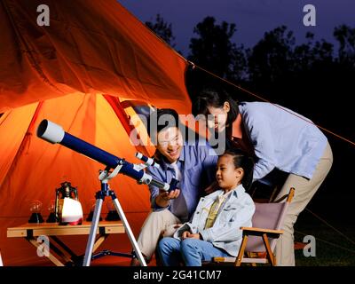 A happy family of three using telescopes outdoors high quality photo Stock Photo