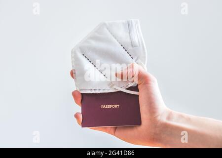 Passport pandemic vacation concept: Close up of fingers holding a passport, ffp2 protection mask, â€œpassportâ€ Stock Photo