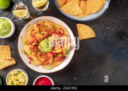 Nachos, Mexican tortilla chips, with tequila on a black background Stock Photo