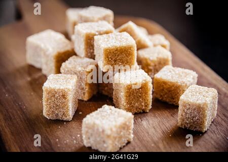Brown cane sugar cubes on a cutting board Stock Photo