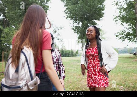 A group of three friends chatting in the university park Stock Photo