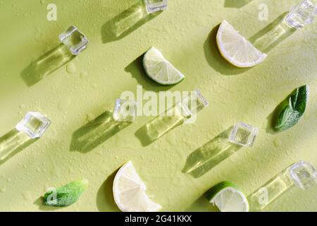 Fresh mint leaf and ice cubes with droplets and lime on green background Stock Photo