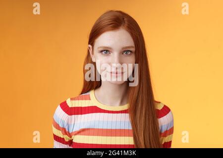 Attractive young sincere redhead girl clean pure perfect skintone smiling modest look camera friendly delighted standing relaxed Stock Photo