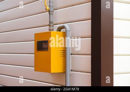 Yellow Gas Meter Box with gas pipes in it on a wall outside the house. Close-up Stock Photo