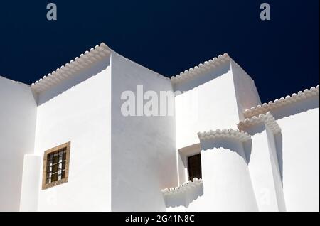 A white residential building set against a dark blue sky. The buildings are built in tradional style architecture in Algarve, Portugal. Stock Photo