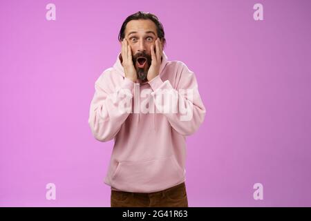 Amused very happy adult bearded dad receive incredible impressive bunch money screaming joyfully touch cheeks widen eyes astonis Stock Photo