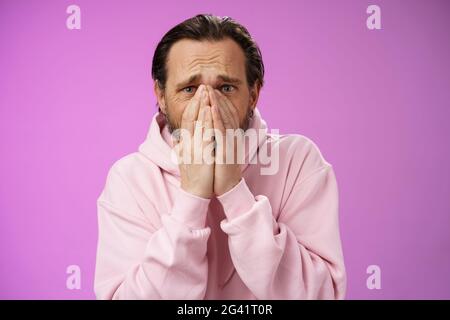 Shocked upset concerned adult husband grieving look heartbroken suffer sorrow distressed feelings frowning hold hands supplicati Stock Photo