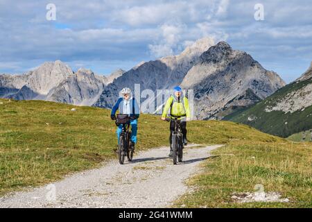 Two mountain bikers ride on Almstrasse, Karwendel in the background, Hochalmsattel, Karwendel, Karwendel Nature Park, Tyrol, Austria Stock Photo
