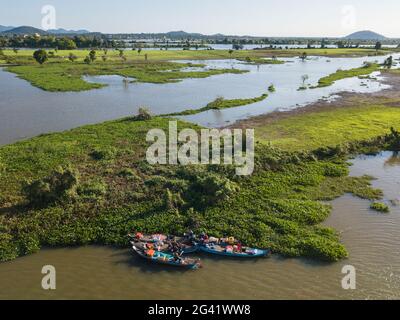 Aerial view of fishermen on a group of longtail boats along the banks of the Tonle Sap River with flooded rice fields behind, near Kampong Chhnang, Ka Stock Photo