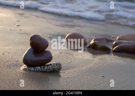 smooth dark stones lie on wet sand by the sea. Sunny day on the Baltic Sea. Close-up. Stock Photo