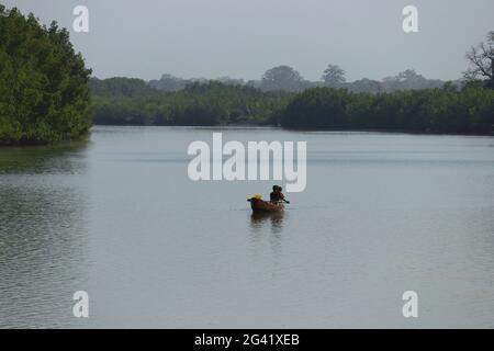 Gambia; Western Region; Boat on the Bintang Bolong; three boys are sitting in the boat; drive towards the harbor Stock Photo