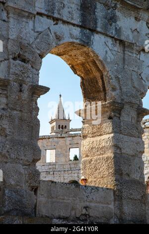 Church tower seen through archway of Roman amphitheater, Pula Arena, Pula, Istria, Croatia, Europe Stock Photo