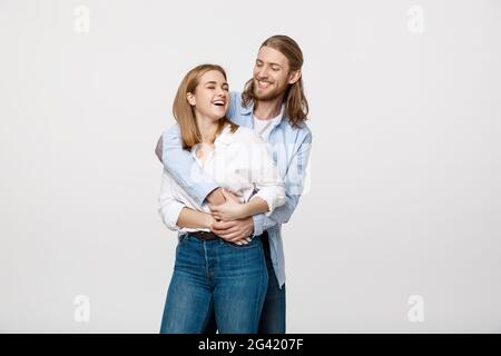 Portrait of cheerful young couple standing and hugging each other on isolated white background Stock Photo