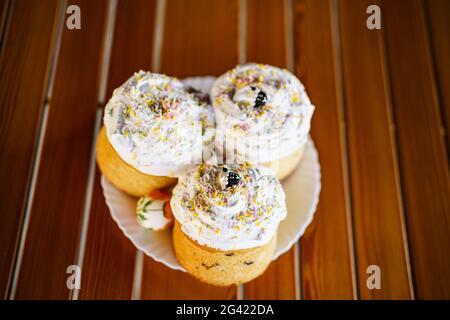 Three Easter cakes on a plate on a wooden table. Stock Photo