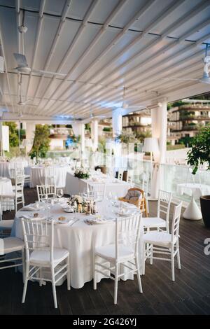 Wedding dinner table reception. Round banquet table with white tablecloth and white Chiavari chairs. Wedding under the tent. Stock Photo