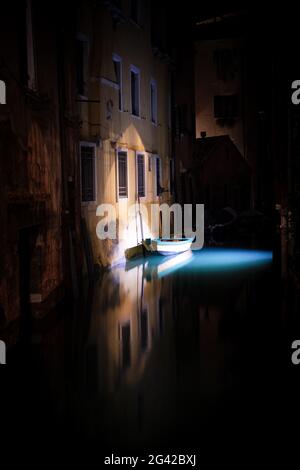 View of a lighted boat and fish in a canal in San Marco at night, Venice, Veneto, Italy, Europe Stock Photo