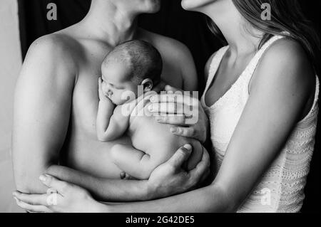 Mother and father holding their newborn baby at a newborn photoshoot Stock Photo