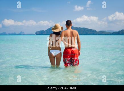 Romantic couple in love hugging on tropical beach enjoying warm ocean water Stock Photo