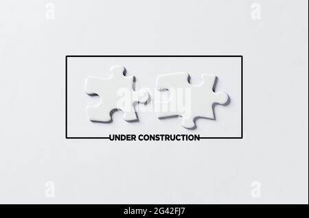 Under construction message with two separated puzzle pieces. Website construction or maintenance concept. Stock Photo