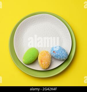 Decorative easter eggs in a round white ceramic plate on a yellow background Stock Photo