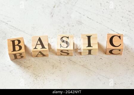 Five wooden cubes with word BASIC on white stone like board, view from above Stock Photo