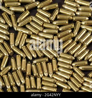 Many brass gun bullets on black table closeup view from above Stock Photo