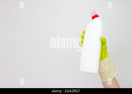 Spring cleaning concept. Top view of hand in yellow rubber gloves holding bottle of detergent on grey background. Cleaning supplies concept Stock Photo
