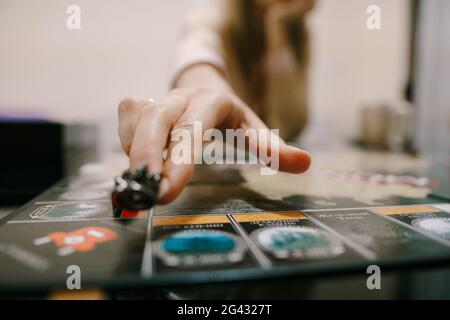 Woman's hand moves figurine in board game, close-up. Home board games Stock Photo