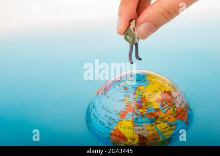 Figurine on the top of the globe in water Stock Photo