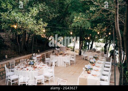 Wedding dinner table reception. Round tables with white tablecloths, brown runners, bouquets flowers, Chiavari chairs, menu sin- Stock Photo
