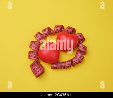 Red heart and red measuring tape on yellow background Stock Photo