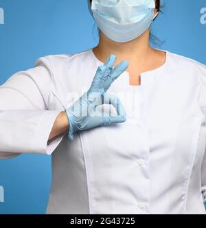 Woman in white coat, wearing blue medical latex gloves on her hands Stock Photo