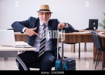 Old male employee preparing for travel in the office Stock Photo