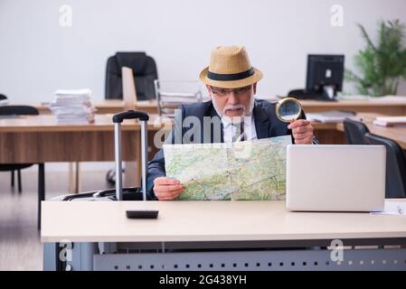 Old male employee preparing for travel in the office Stock Photo