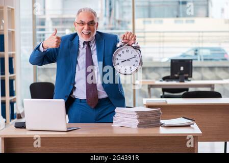 Old male boss employee in time management concept Stock Photo