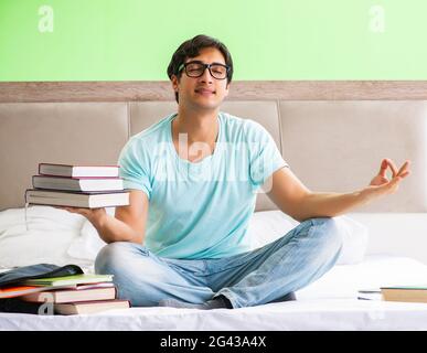 Student preparing for exams at home in bedroom sitting on the be Stock Photo