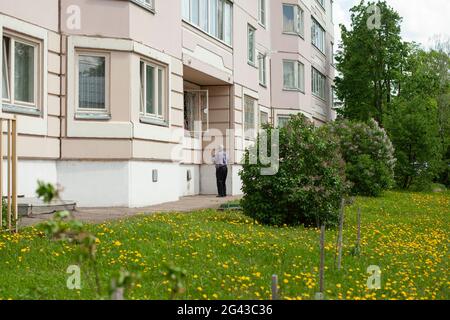 Apartment building ground floor of a building. An elderly man passes something out the window. Stock Photo