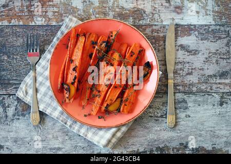 A plate with baked carrots. Baked carrots in strips with herbs and spices. Stock Photo