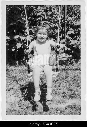 Three Old Girl Plays on aBackyard Swing, 1952, USA Stock Photo