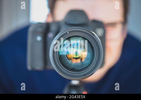 Photographer at work: Man is standing behind a professional camera on a tripod, making pictures Stock Photo