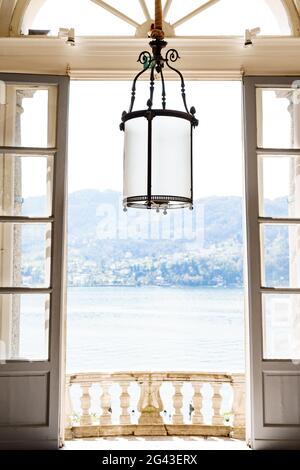 View from the balcony and from the window from an old villa on Lake Como in Italy. Antique forged lamp with a large shade. Stock Photo